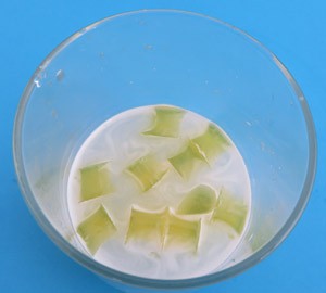 Yellow Jell-O cubes in a plastic cup filled with white proteases solution
