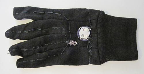 Conductive thread sprayed with paint, a switch and a battery holder sewn onto the back of a glove