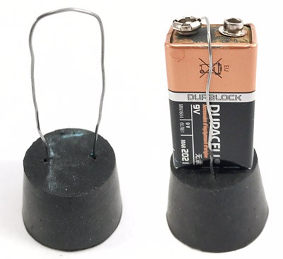 A wire loop inserted into a rubber stopper holds a 9 volt battery in place