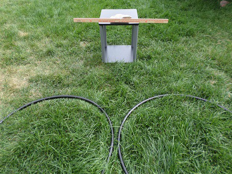 Two hula hoops lying in teh grass in front of a yard stick.