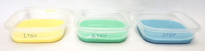 Three plastic containers filled with yellow, green and blue slime