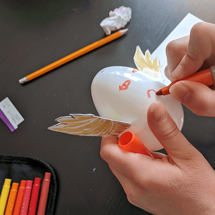 Student holding a plastic Easter egg decorated with a face and with cardboard wings added