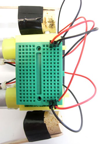 Wires from a battery pack and two DC motors are connected to a mini breadboard
