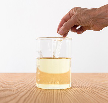 A glass rod in a glass of yellow liquid