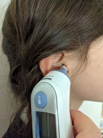 Girl using an ear thermometer to take her picture.
