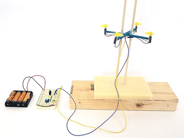 Drone hovering on guide poles while connected to altitude control circuit