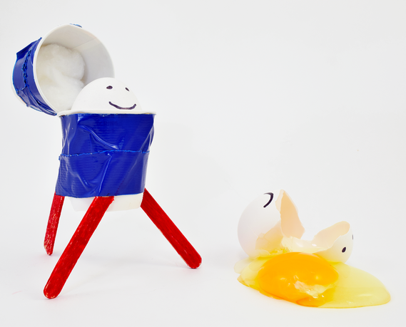 An egg with a protective landing device attached for egg drop experiment next to a cracked egg