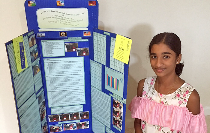 A student standing in front of a science fair display board