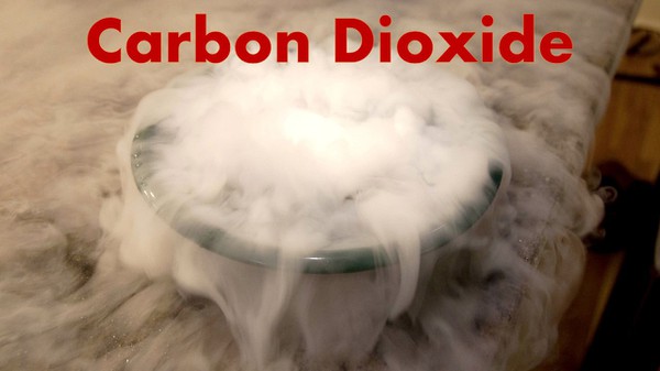 A bowl of dry ice with carbon dioxide gas spilling over the sides and all over the table.  