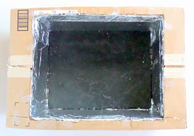 A piece of cardboard painted black is placed in a cardboard box lined with aluminum foil