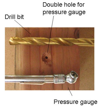 A countersunk hole is drilled into a wooden board to accommodate the head of a pressure gauge