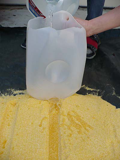 Water from a plastic jug flows into a trench made on the surface of a pile of sand