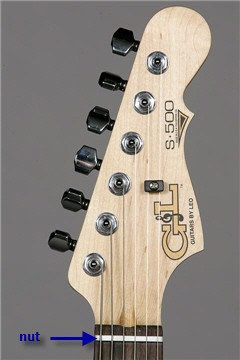 Close up photo of an electric guitar headstock shows the nut and tuning machines