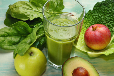 Green smoothie surrounded by fruits and vegetables