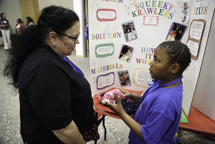 A woman talking to a student in front of a display board