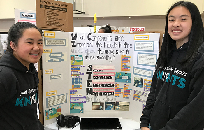 Two students standing in front of a science fair display board