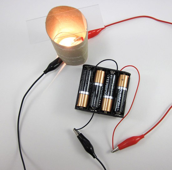 An enclosed lightbulb is connected to a battery pack with two wires