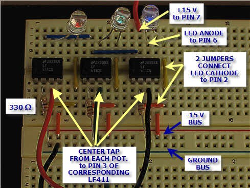Three different colored LEDs and three dual-inline packages are connected to resistors with jumper cables on a breadboard