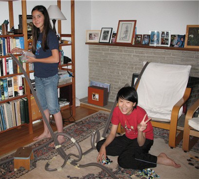 Two women setup a marble rollercoaster made up of cut foam pipe insulation