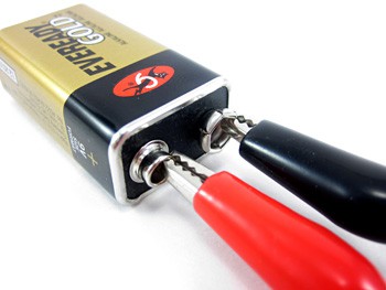 Two alligator clips attached to the terminals of a nine volt battery