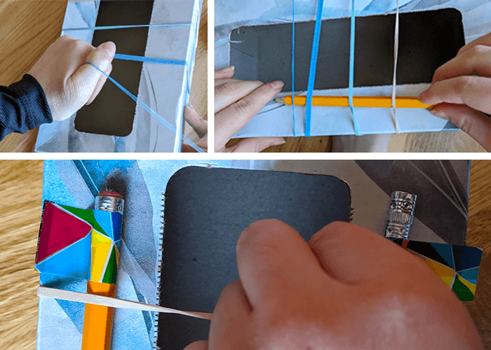 Student stringing rubber bands, adding pencils, and then taping pencils underneath the rubber rubber bands stretched around the tissue box