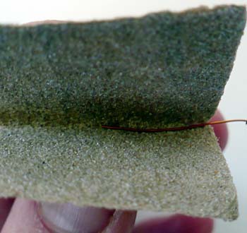 Sandpaper is used to remove any insulation from the end of a copper wire