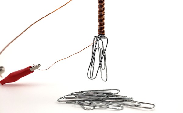Paperclips are attracted to an electromagnet made from wires and a nail