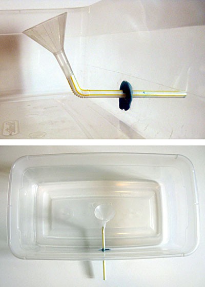A small funnel is attached to a straw and the straw is placed through the wall of a plastic container