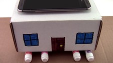 A cardboard house sitting on markers with a cell phone on top for an earthquake lesson plan