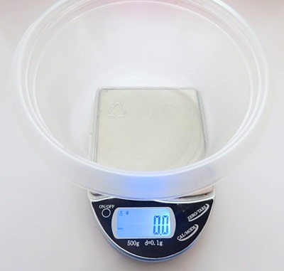 A scales measurements are set to zero with a plastic container on top