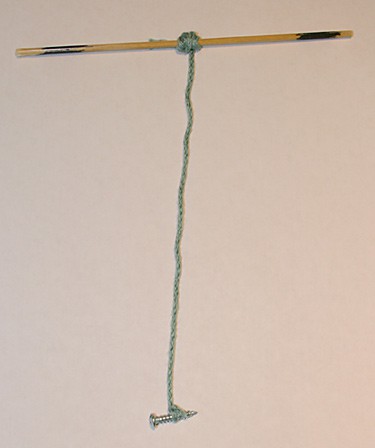 The middle of a wooden skewer is tied to one end of a string and a small screw is tied to the other end