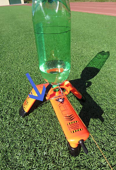 An Aquapod bottle launcher is secured to the ground with a metal U-peg