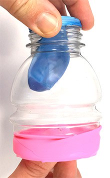 The top-half of a cut plastic bottle is covered on both ends by deflated balloons