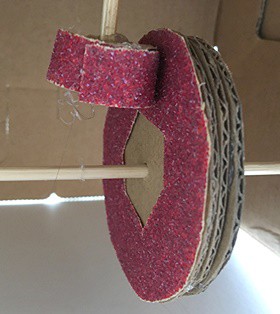  A circle spiraling out treaded on an axle with a flat piece of cardboard resting on the spiral.  