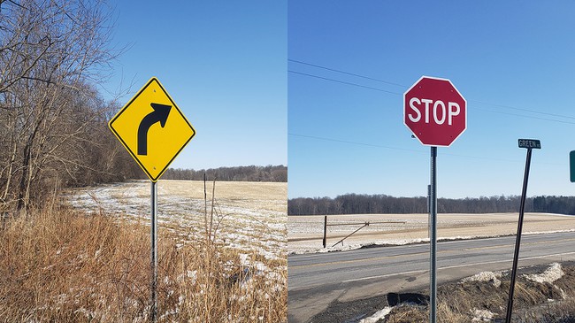 A 'curve ahead' sign and a stop sign along the side of the road at two different locations, with farmland, trees and blue sky in the background. 