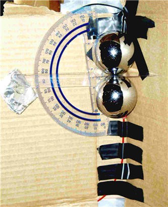 In the inner crease of a piece of folded cardboard two condutive spheres are seperated by a thin sheet of plastic