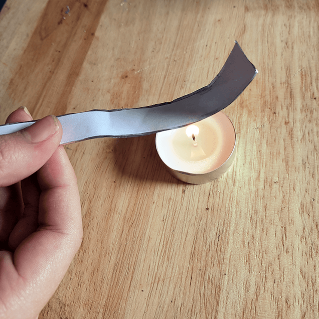 Example of aluminum foil and paper strip being held over a flame and curling
