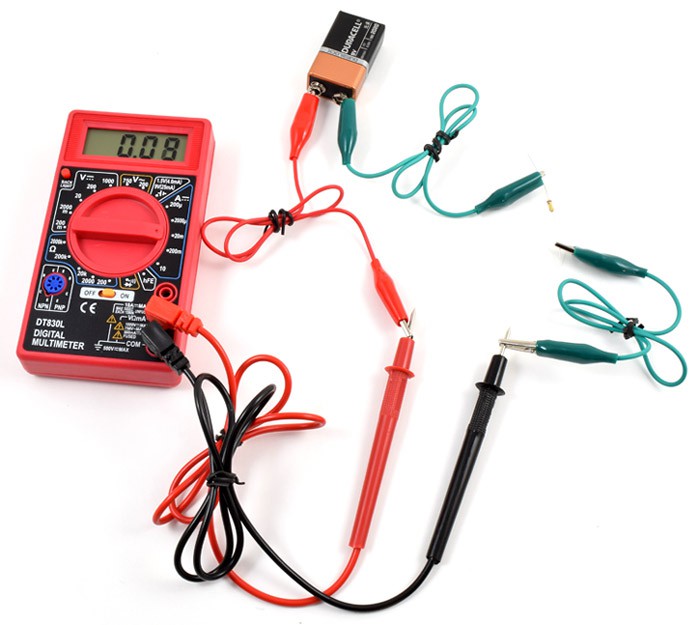 Alligator clips connect the leads of a multimeter to a nine volt battery and a resistor in a closed circuit
