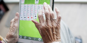 a wrinkled pair of hands playing a card game on a tablet / coding project