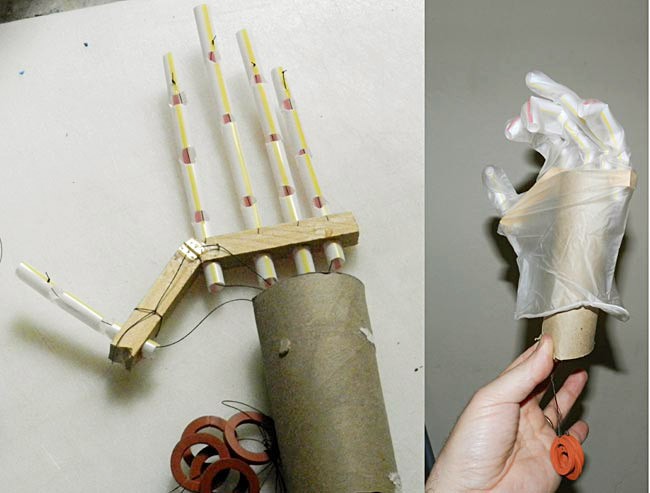 A homemade prosthetic hand made from straw, springs, strings, wood and cardboard