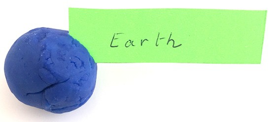 The corner of a label reading 'earth' stuck in a play dough ball 