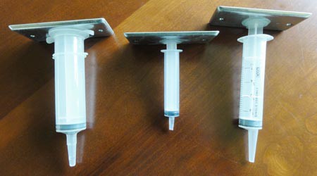 Metal plates are placed on the plungers of three different sized syringes