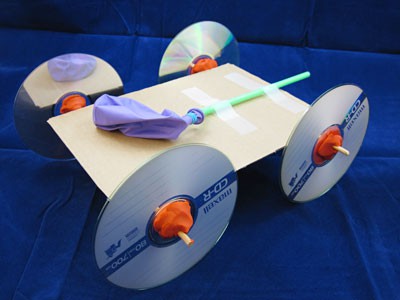 A balloon-powered car made from cardboard, clay, CDs, tape, wooden skewers, a straw and a balloon
