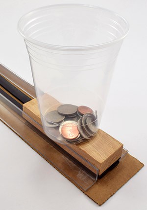 A cup of coins rests on a model maglev train