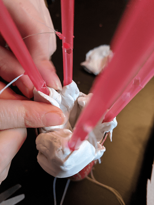 Student adjusting straw robot fingers in clay as part of a robot hand