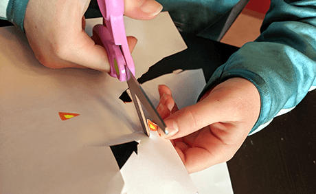 Student using scissors, straws, and strings to make jointed fingers for a robot hand