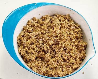 Organic material that looks like small wood chips in a bowl. The contents of this bowl looks similar to the contents of the bag in Figure 4. 