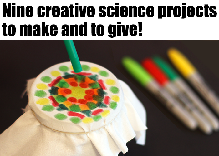 A cloth decorated with colorful ink dots is stretched over a cup and held with a rubber band