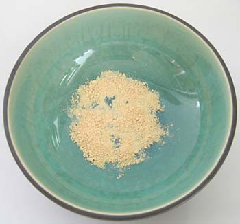 A vitamin C tablet is crushed into orange powder in a bowl