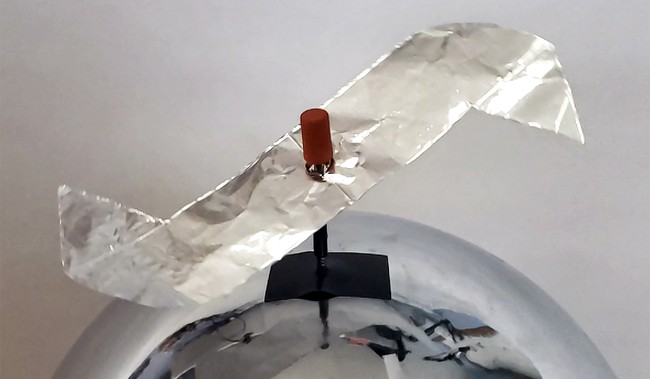 A rotor made from aluminum foil with pointed tips, mounted on a nail on top of a van de graaff generator.